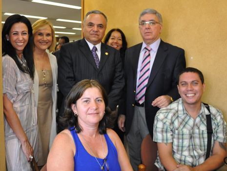 Maria da Penha (sentada, de azul) comemora o acordo com a CEF. Em pé, Morgana Richa, Liliane Roriz, Nelson Tomaz Braga, Lúcia Menezes (da CEF) e Paulo Espirito Santo