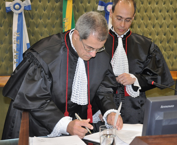 Marcelo Pereira da Silva assina o termo de posse. Ao lado, Sergio Schwaitzer