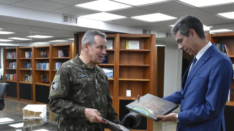 Na foto, o General Tomás presenteia o presidente do TRF2, Guilherme Calmon, com exemplar de livro sobre a história do Exército Brasileiro
