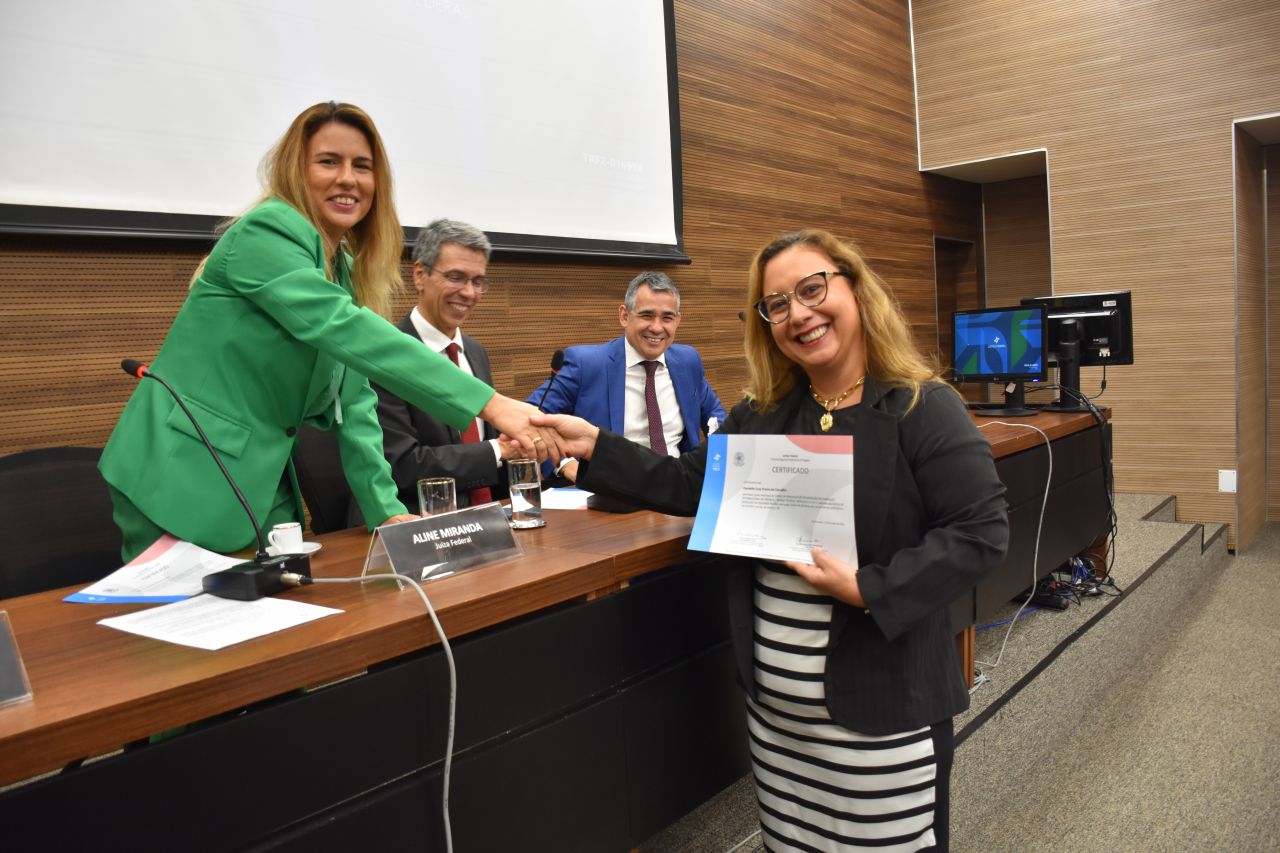 Na foto, a juíza federal Aline Miranda aperta a mão e entrega certificado de conclusão para uma das formandas